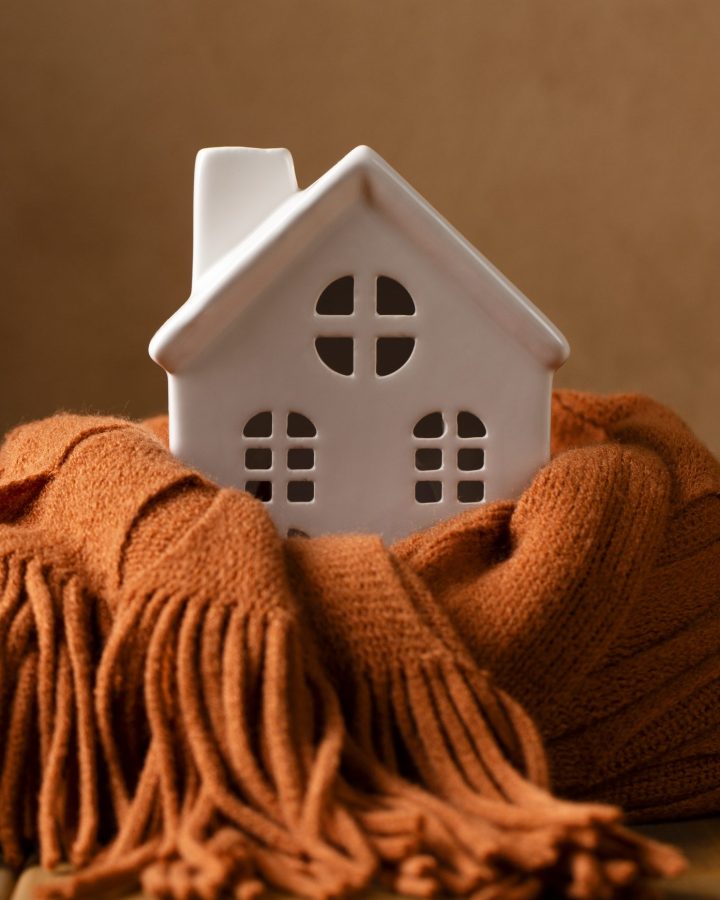 photo of cozy white ceramic house set in rust colored scarf